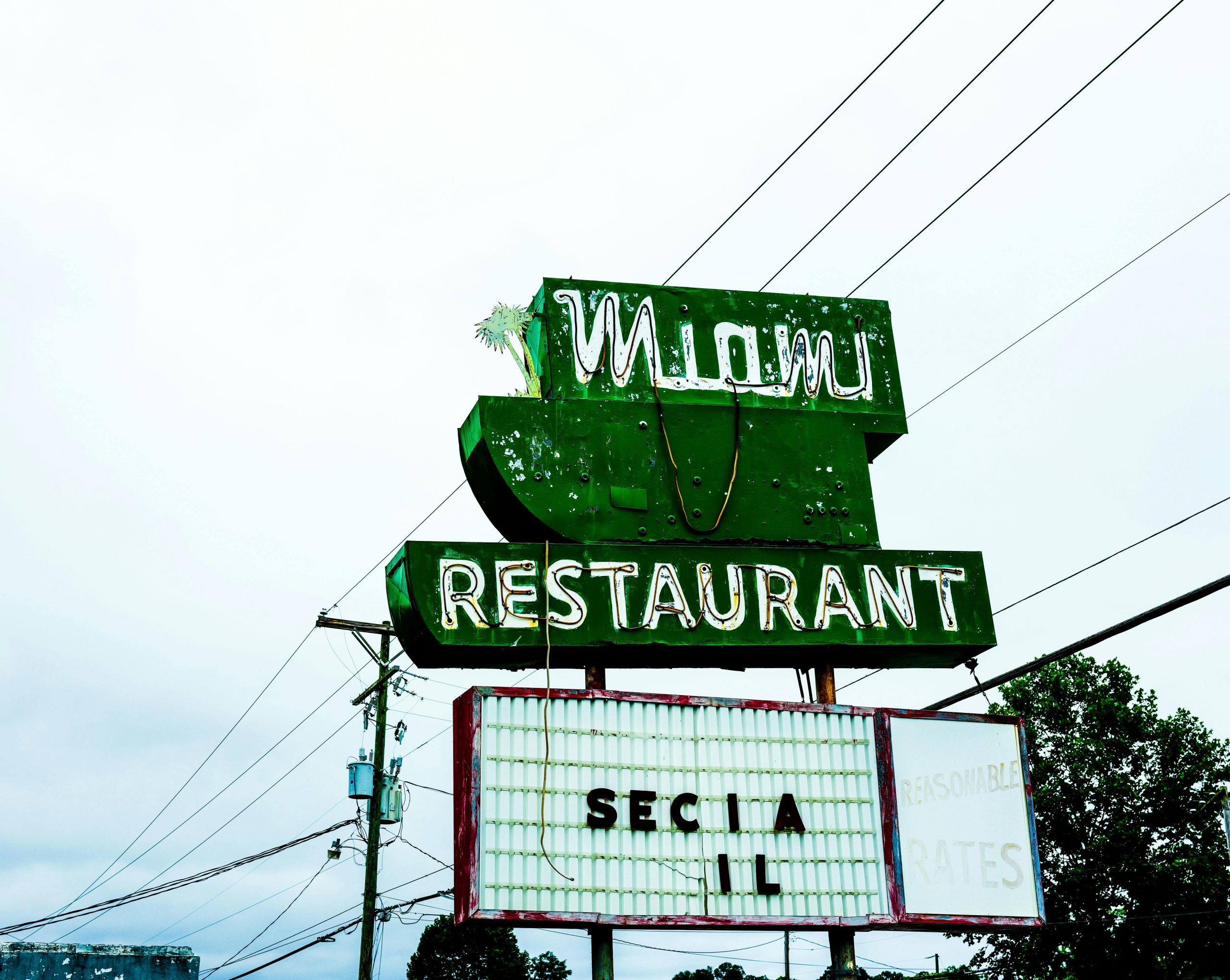 Retro Miami restaurant sign with neon lights on a cloudy day.